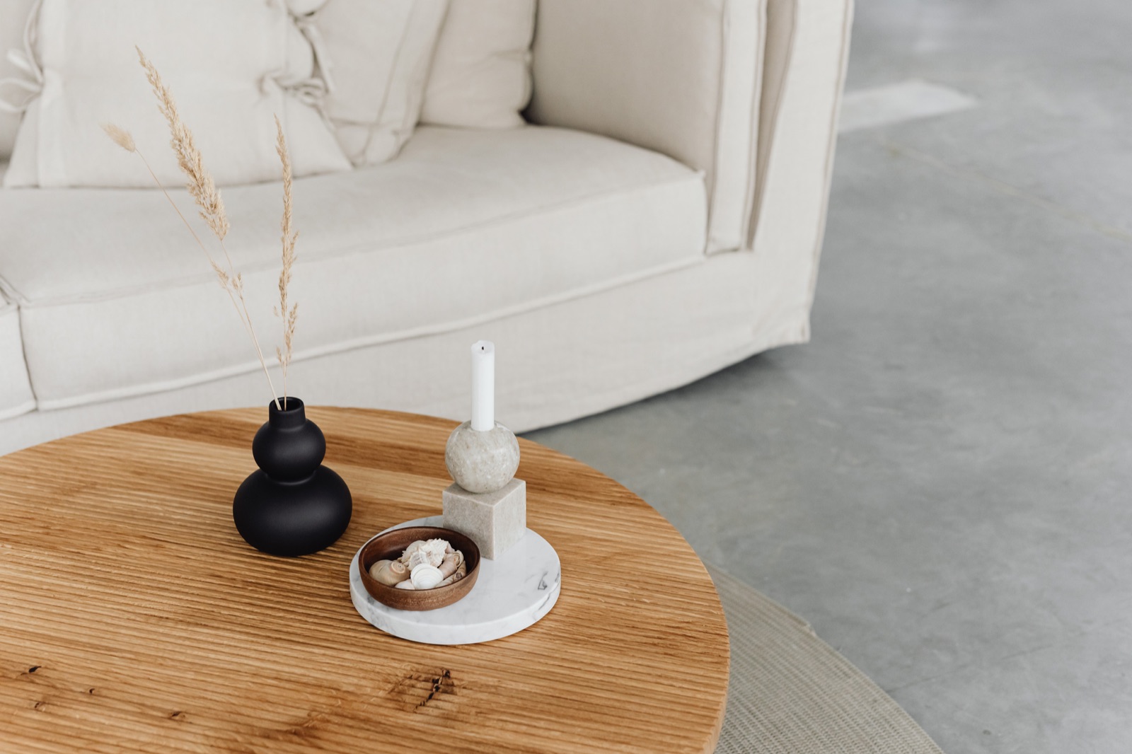 Detalhe de mesa de centro de madeira com vaso e velas sobre tapete de fibra natural